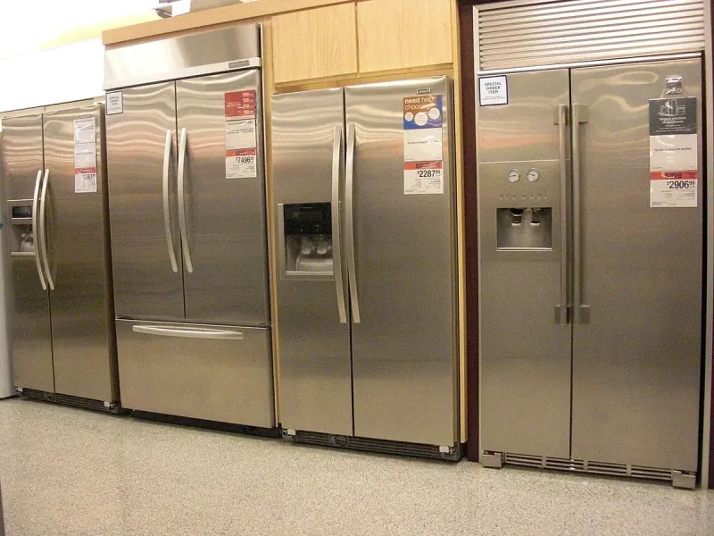 Certified refrigeration technician diagnosing and inspecting a large upright freezer unit in Boston MA