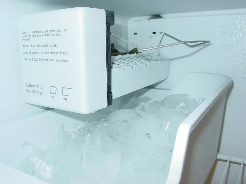 Professional technician servicing a high-end under-counter ice maker machine with crystal clear ice cubes