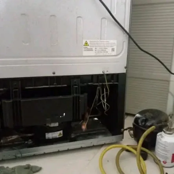 Certified technician performing sealed system linear compressor replacement on modern French door refrigerator in Boston MA