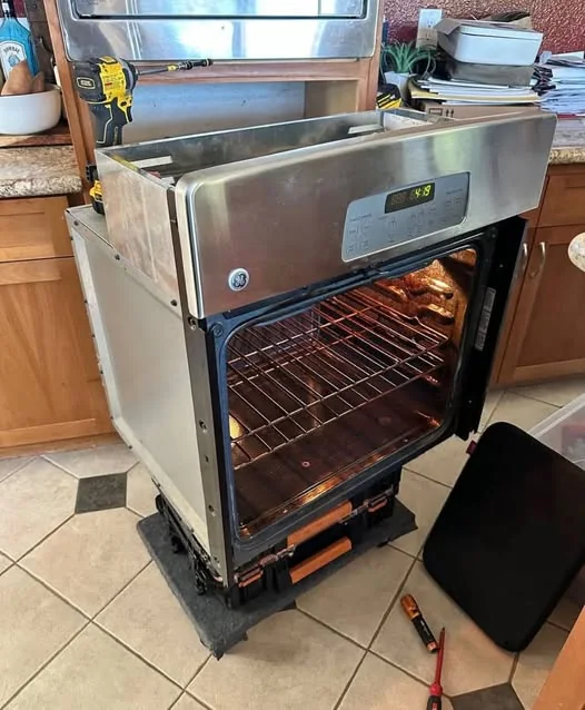 GE Monogram built-in wall oven on technician dolly with tools on tile floor in Greater Boston