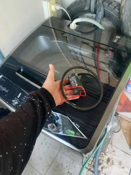 Technician holding replacement washing machine run capacitor and drive belt in Seaport Boston